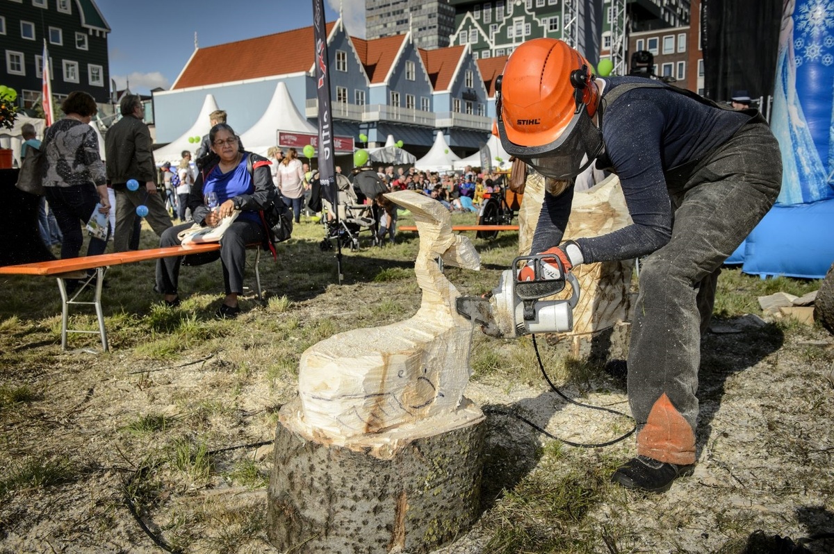 Foto van de uitmarkt in Zaanstad met daarop een kunstwerk uit hout en publiek, genomen door fotograaf Mike Bink